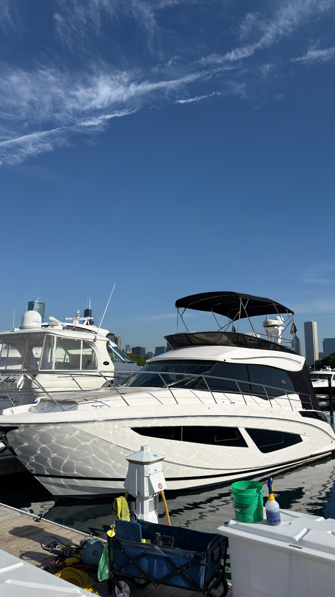 White motor yacht moored at a Chicago harbor with the downtown skyline and a bright blue sky